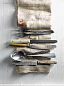 Old cutlery on a linen cloth (seen from above)