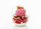 A strawberry ice cream sundae in a glass with flaky pastry
