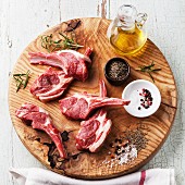 Raw fresh lamb ribs with salt, pepper and cumin on wooden cutting board on blue background