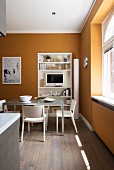 Modern dining table in front of shelving unit in kitchen with yellow walls