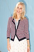 Blonde Frau in weißem Rock, grauer Bluse und gestreiftem Cardigan