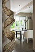 Wooden sculpture in front of black dining table and designer chair