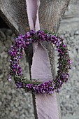 Romantic heather wreath hung from rustic wooden upright