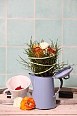 Arrangement of ranunculus and bilberry twigs in old enamel coffee pot