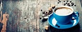 Blaue Kaffeetasse und Kaffeebohnen auf Vintage Holzuntergrund