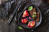 Sliced salmon filet, salted with beetroot juice, served on whole wheat toasts with salad leaves