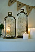 Fairy lights in two candle lanterns amongst lit candles