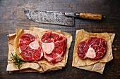 Raw fresh cross cut veal shank for making Osso Buco on wooden background with meat cleaver