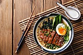 Duck noodles with egg and pak choi cabbage in bowl on wooden background