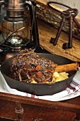 Radicchio braised lamb shank on black cast iron skillet with oil lamp in background