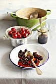 Cherry jam on a plate, fresh cherry in aluminum colander and dutch pot with cherry jam on background