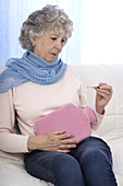 Woman with hot water bottle and thermometer