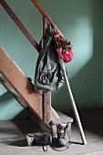 Vintage knapsack, walking stick and bundle of red rose hips on handrail of vintage staircase