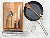 Various kitchen utensils: pan, spatula, knife, measuring cup, aluminium foil