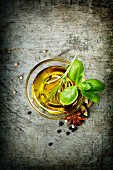 Olivenöl, Kräuter und Gewürze auf rustikalem Untergrund