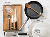 Various kitchen utensils: pan, grater, salad bowl, glass bowl, knives, spoon
