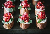 A group of strawberry bruschettas with ricotta cheese and arugula