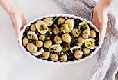 Baby Potato Salad with Sun-Dried Tomatoes and Caper Dressing is served in an oval white bowl
