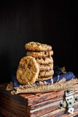 Stapel Chocolate Chunk Cookies auf Holzkiste vor schwarzem Hintergrund
