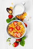 Healthy Breakfast with corn flakes, milk and strawberry on old wooden background