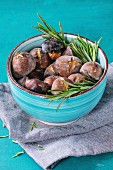 Roasted chestnuts in the ashes with rosemary in turquoise ceramic bowl