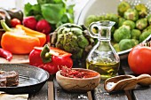 Stillleben mit frischem Gemüse, Gewürzen, Öl und Fleisch in Pfanne