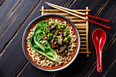 Miso Ramen Asian noodles with beef and pak choi cabbage on dark wooden background