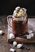 Hot chocolate with homemade marshmallow, chocolate chips and syrup in mason jar