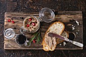 Glass jars of chicken liver pate with blackcurrant jam, pomegranate grain and sliced bread