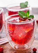 Cranberry cocktail with mint garnish on a wooden table