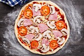 Pizza zubereiten: Pizza mit Schinken, Tomaten und Pilzen belegen