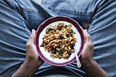 A bowl of Spicy Pumpkin Granola is in the hands of a man