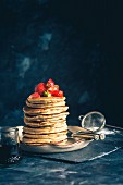 Stack of Gluten free Oat Flour Pancakes served with chopped Strawberries and Maple Syrup
