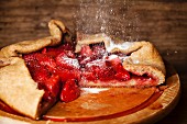 Strawberry pie and powdered sugar on wooden background