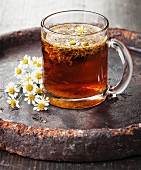 Chamomile tea with chamomile flowers on dark background