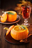 Pumpkin soup in a small pumpkin with leaf of sage