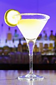 Ein Cocktail mit Limette im Glas auf Bartheke in Cocktailbar