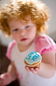 Rothaariges Mädchen hält Muffin mit Zuckerglasur und der Aufschrift Love You
