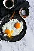 A fried egg with salt and a cup of coffee