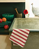 Red-and-white-striped tea towel draped over the edge of a stone sink