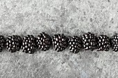 Row of blackberries on a grey metal surface