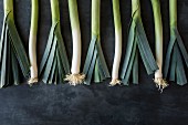 Row of leeks on a grey stone surface