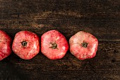 Row of pomegranates on a wooden surface