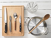 Various kitchen utensils: pot, measuring cup, knife, spoon, peeler