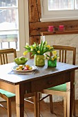 Tulips in vase with knitted cover on old wooden table