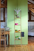 Ladder shelves leaning against green partition in attic room