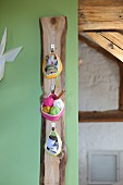Three crocheted basket hung from hooks on wooden board