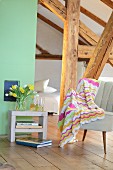 Crocheted blanket with zigzag pattern draped over retro armchair in attic room