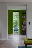 Blick auf einen Stuhl vor grüner Wand und schmalem Fenster