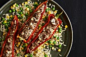 Red pointed pepper filled with minced beef and quark on a bed of rice with sweetcorn and peas
